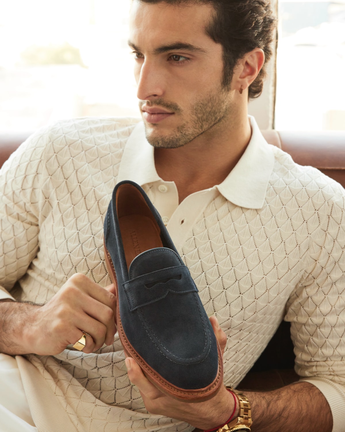 A man holding a black suede penny loafer. 