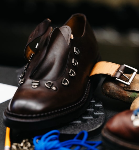 An angled view of a brown unbuckled hiking shoe without laces.