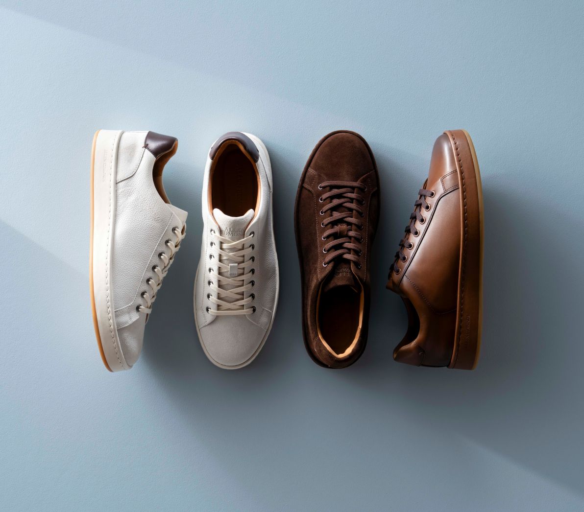 Four Allen Edmonds Barnes Lace-up sneakers arranged in a row, featuring two in white leather, one in brown suede, and one in coffee brown leather.